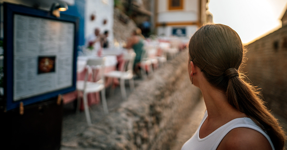 A woman looking at a menu to decide where to eat in Ibiza this 2021